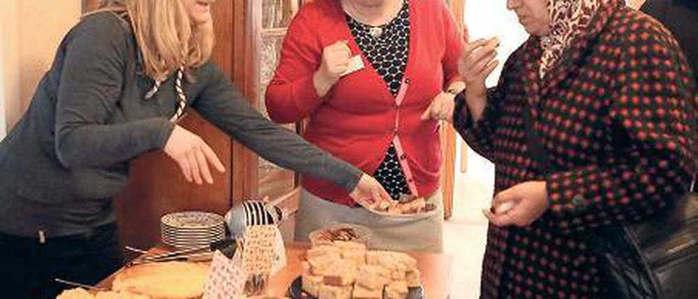 Vermittlerin. Café-Leiterin Martina Kruse (M.) mit Gästen.