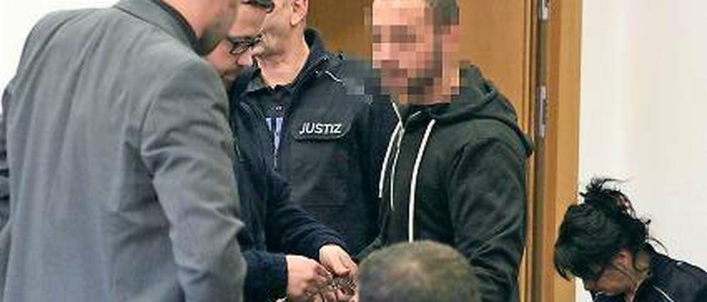 In Handschellen. Ein Angeklagter (r.) kurz vor der Urteilsverkündung.
