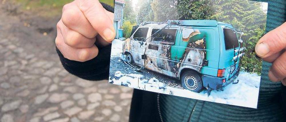 Brandanschlag. Eine ehrenamtliche Flüchtlingshelferin hält ein Foto in der Hand, das ihren ausgebrannten Campingbus zeigt. Sie und ihr Mann sind Opfer eines Brandanschlags geworden.