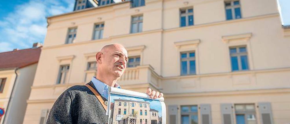 Vorher-Nachher-Effekt. Matthias Seeger vom Sanierungsträger zeigt den ehemaligen Zustand des Hauses in der Fischerstraße. Im Hintergrund das sanierte Gebäude.