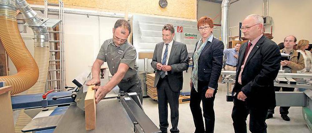 Passt, wackelt und hat Luft. René Batzer an der Kreissäge in seiner neuen Werkstatt. Jakobs, Schneider und Schramm schauen zu.