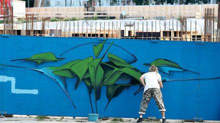 Ein Graffiti-Künstler besprüht am Samstag die Wand entlang der Baustelle zum neuen Brauhausbad.