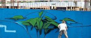 Ein Graffiti-Künstler besprüht am Samstag die Wand entlang der Baustelle zum neuen Brauhausbad.