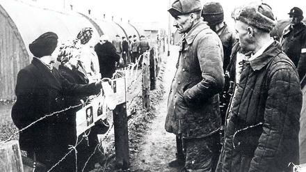 Fremde Welt. Kriegsheimkehrer stehen Frauen mit Suchschildern im Grenzdurchgangslager Friedland gegenüber.