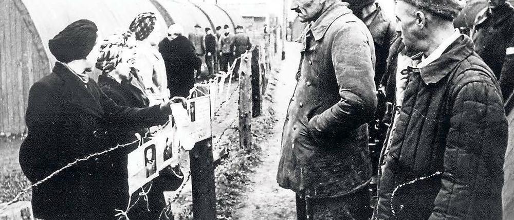 Fremde Welt. Kriegsheimkehrer stehen Frauen mit Suchschildern im Grenzdurchgangslager Friedland gegenüber.