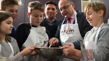 Christian Schmidt (CSU), Bundesminister für Landwirtschaft und Ernährung, und TV-Koch Tim Mälzer (M) kochen zusammen mit Schülern.