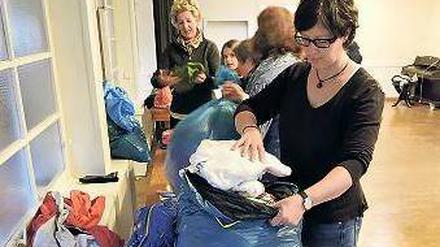 Eingetütet. Beate Apelt sortiert mit anderen Helfern die Kleinderspenden.