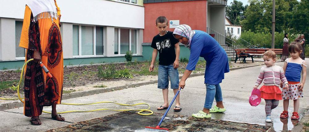 Angekommen in Teltow. Frauen reinigen auf dem grauen Betonhof vor dem Heim ihre Teppiche. Arbeiten gehen dürfen die Menschen aus dem Tschad oder Afghanistan nicht.