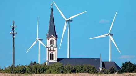 Windräder hinter der Kirche von Ragewitz (Sachsen). Die Windräder der neuen Generation sind allerdings viermal so hoch wie mancher Kirchturm.