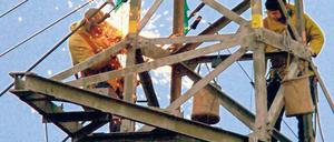Bald zappenduster? Zwei Monteure kontrollieren einen Strommast.