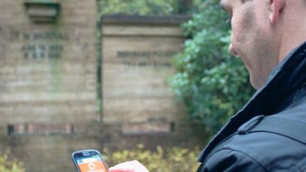 Nachgeschaut. Besucher sehen auf dem Handy Informationen zu den Toten.