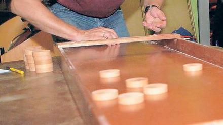 Die Pucks müssen in die Garage. Beim Flutschbrettspiel ist Geschicklichkeit gefragt. Im Café 11-line treffen sich Fans regelmäßig zum Turnier – auch Neuanfänger sind willkommen.