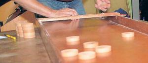 Die Pucks müssen in die Garage. Beim Flutschbrettspiel ist Geschicklichkeit gefragt. Im Café 11-line treffen sich Fans regelmäßig zum Turnier – auch Neuanfänger sind willkommen.