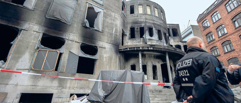 Ursache unbekannt. Ein Polizeibeamter steht vor dem nach einem Feuer am 11. August beschädigten Neubau der Meylana-Moschee in Kreuzberg. Nach neuesten Erkenntnissen kann Brandstiftung nicht ausgeschlossen werden.