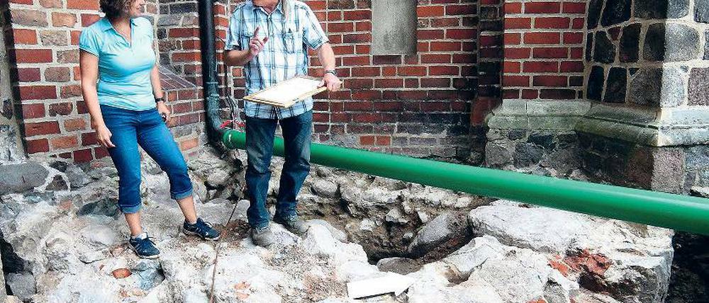 Geheimnis unter der Kirche. Der Feldsteinring im Vordergrund könnte das Fundament eines Burgturms gewesen sein – oder eines Brunnens. Archäologe Michael Böhm und Annett Pratsch von der Unteren Denkmalschutzbehörde des Landkreises untersuchten die Fundstelle.