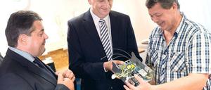 Spart Treibstoff. Sigmar Gabriel (l.) und Dietmar Woidke lassen sich von einem Veinland-Mitarbeiter ein Gerät zeigen, das Hochseeschiffe effizienter machen soll.