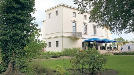 Drinnen kühl, draußen Café. Die Villa Schöningen an der Glienicker Brücke zeigt derzeit Werke von Olaf Metzel unter dem Titel „Umsonst und Draußen“. Ein Argument für den Besuch kann bei großer Hitze aber auch die Klimaanlage des Hauses sein.