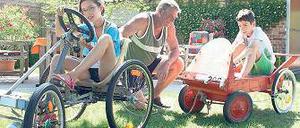 Training im Garten. Sophie, Lukas und der Großvater mit ihren Seifenkisten.