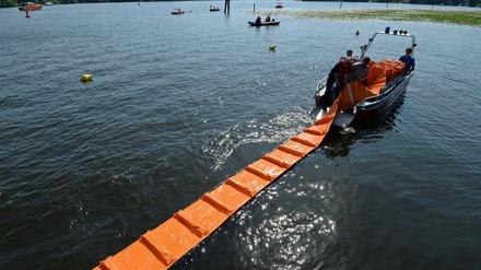 Nach dem Ölunfall auf der Havel in Potsdam: Feuerwehrleute bringen eine Ölbarriere aus.