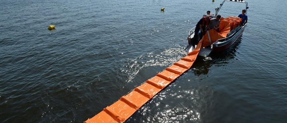 Nach dem Ölunfall auf der Havel in Potsdam: Feuerwehrleute bringen eine Ölbarriere aus.