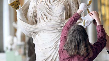 Zurück in der „Schönsten der Welt“. Die antike Figur einer Betenden mit dem Porträtkopf der Kaiserin Sabina wird in der historischen Bildergalerie des Schlosses Sanssouci von Restauratoren in Augenschein genommen.