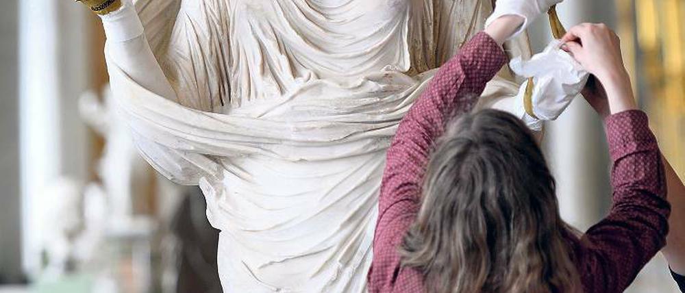 Zurück in der „Schönsten der Welt“. Die antike Figur einer Betenden mit dem Porträtkopf der Kaiserin Sabina wird in der historischen Bildergalerie des Schlosses Sanssouci von Restauratoren in Augenschein genommen.