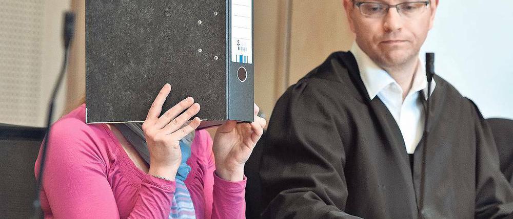 Prozessauftakt. Die Angeklagte Maika M. verdeckt ihr Gesicht hinter einem Aktenordner – neben ihr Anwalt Stefan Böhme am Dienstag im Landgericht in Frankfurt (Oder). Die 22-jährige Mutter soll den kleinen neugeborenen Jungen erstochen haben.