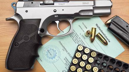 Registriert. Eine Kaliber 9 mm Pistole, Patronen und ein Magazin liegen auf einer Waffenbesitzkarte.