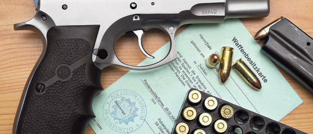 Registriert. Eine Kaliber 9 mm Pistole, Patronen und ein Magazin liegen auf einer Waffenbesitzkarte.