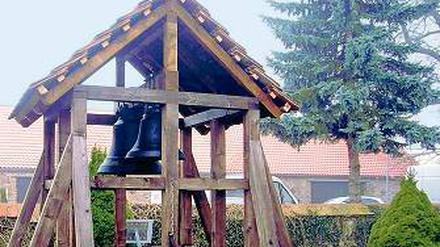 Wieder am Tageslicht. Die alten Glocken hängen in einem Holzgestell.