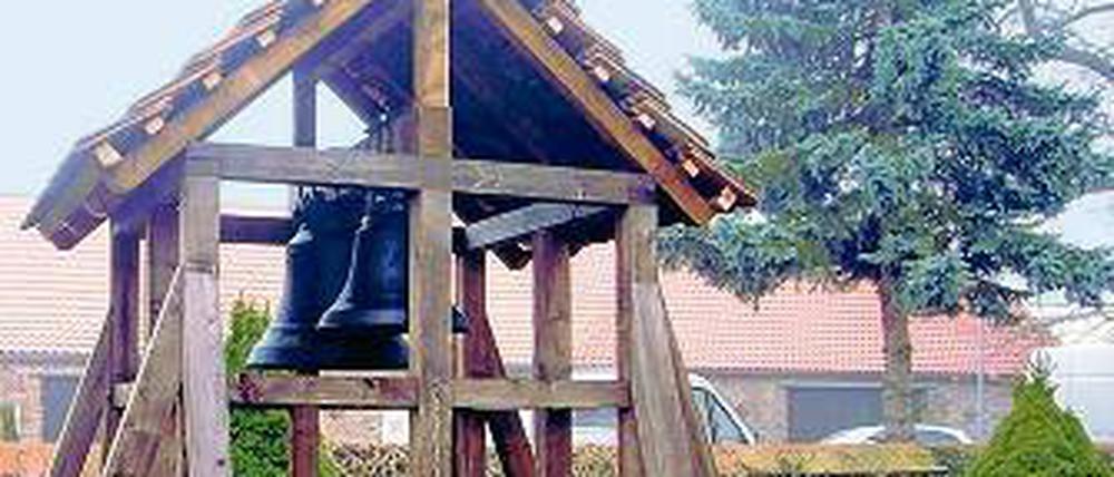 Wieder am Tageslicht. Die alten Glocken hängen in einem Holzgestell.