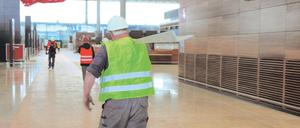 Dauerbaustelle. In der künftigen BER-Abflughalle eilen statt Fluggästen bislang nur Bauarbeiter hin und her. Über den theoretisch fast betriebsfertigen Schaltern hängt Pae Whites Skulptur „Fliegender Teppich“ unter der 22 Meter hohen Terminal-Halle.