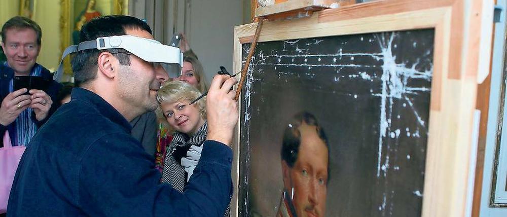 Millimeterarbeit. Daniel Fitzenreiter zeigt den Sängern der Komischen Oper Berlin, wie die Bildrestauratoren im Neuen Palais so arbeiten. Die Künstler hatten sich auf den Weg nach Potsdam gemacht, um sich auf ihre Rollen in der nächsten Mozart-Inszenierung einzustimmen.