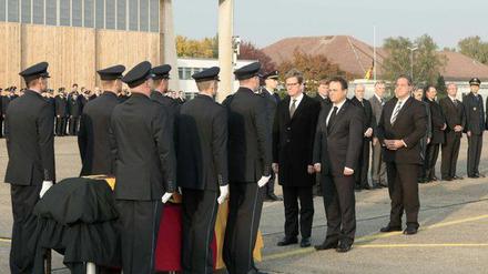 Bundesaußenminister Guido Westerwelle (FDP), Bundesinnenminister Hans-Peter Friedrich (CSU) und der Präsident der Bundespolizei Dieter Romann (l-r) verneigen sich vor dem Sarg mit den sterblichen Überresten des im Jemen getöteten Bundespolizisten.
