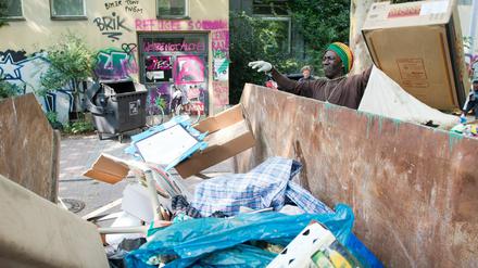 Ein Mann wirft an der ehemaligen Gerhart-Hauptmann-Schule in Berlin-Kreuzberg Müll in einen bereitgestellten Container.