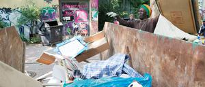 Ein Mann wirft an der ehemaligen Gerhart-Hauptmann-Schule in Berlin-Kreuzberg Müll in einen bereitgestellten Container.