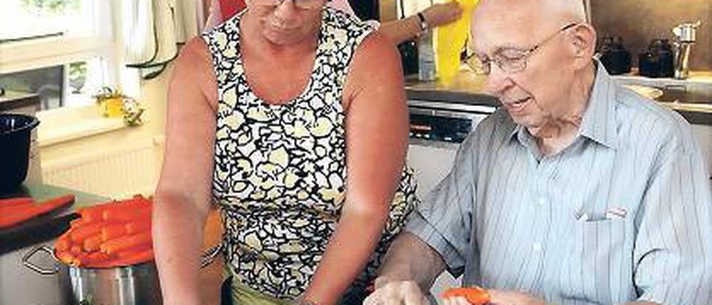 Wie in einer Familie. Doris Grunow bereitet das Mittagessen für die Hausgemeinschaft vor: Bewohner helfen ihr beim Schneiden von Kartoffeln, Möhren und Zwiebeln.