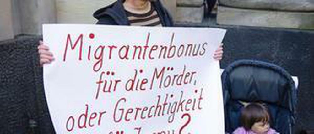 Vor dem Gerichtsgebäude steht am Montag ein Mann mit einem Plakat: "Migrantenbonus für die Mörder oder Gerechtigkeit für Jonny?" ist darauf geschrieben.