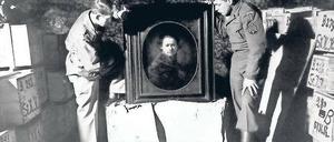 Entdeckung im Bergwerk Heilbronn. Monuments Men Dale V. Ford und Harry Ettlinger (v. l.) nehmen 1945 ein Selbstporträt Rembrandts in Augenschein, das Angestellte aus dem Museum Karlsruhe dort zur Sicherheit hingebracht hatten. Die Kisten links und rechts enthalten weitere Tausende von Kunstwerken, die in der Mine versteckt waren.
