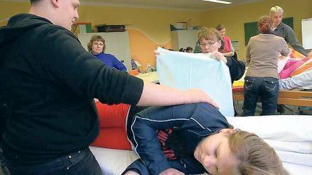 An der Testperson. Während Paul Dähn die Ersatz-Heimbewohnerin in der Seitenlage stützt, soll Olga Becker das Bettlaken wechseln. Zusammen mit 13 anderen werden Dähn und Becker in Strausberg ein Jahr lang zum Altenpflegehelfer ausgebildet.