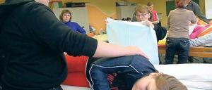 An der Testperson. Während Paul Dähn die Ersatz-Heimbewohnerin in der Seitenlage stützt, soll Olga Becker das Bettlaken wechseln. Zusammen mit 13 anderen werden Dähn und Becker in Strausberg ein Jahr lang zum Altenpflegehelfer ausgebildet.