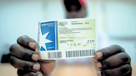 Bargeld statt Gutscheine. Der kenianische Asylbewerber Patrick Kizito zeigt einen Einkaufsgutschein des Unternehmens Sodexo.