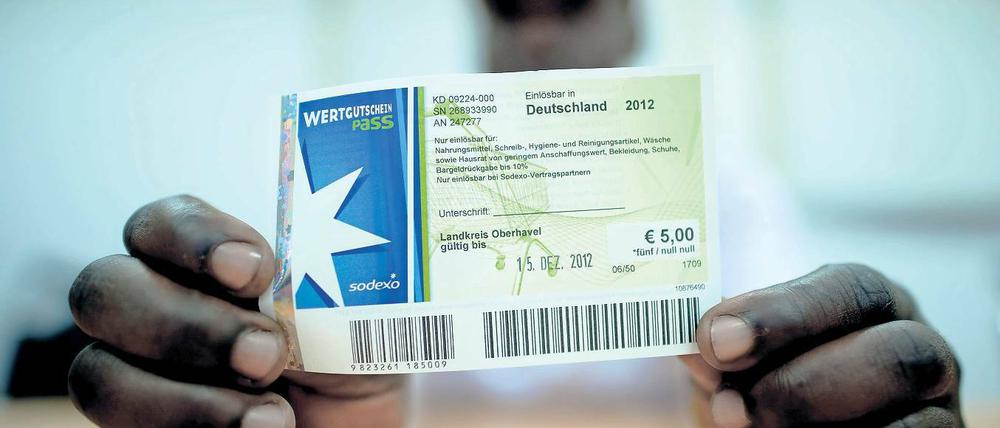 Bargeld statt Gutscheine. Der kenianische Asylbewerber Patrick Kizito zeigt einen Einkaufsgutschein des Unternehmens Sodexo.