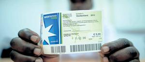 Bargeld statt Gutscheine. Der kenianische Asylbewerber Patrick Kizito zeigt einen Einkaufsgutschein des Unternehmens Sodexo.