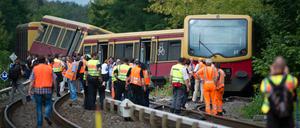 Polizisten und weitere Helfer stehen am Dienstag auf der Bahnstrecke zwischen den Bahnhoefen Tegel und Schulzendorf in Berlin vor den entgleisten Waggons einer S-Bahn.