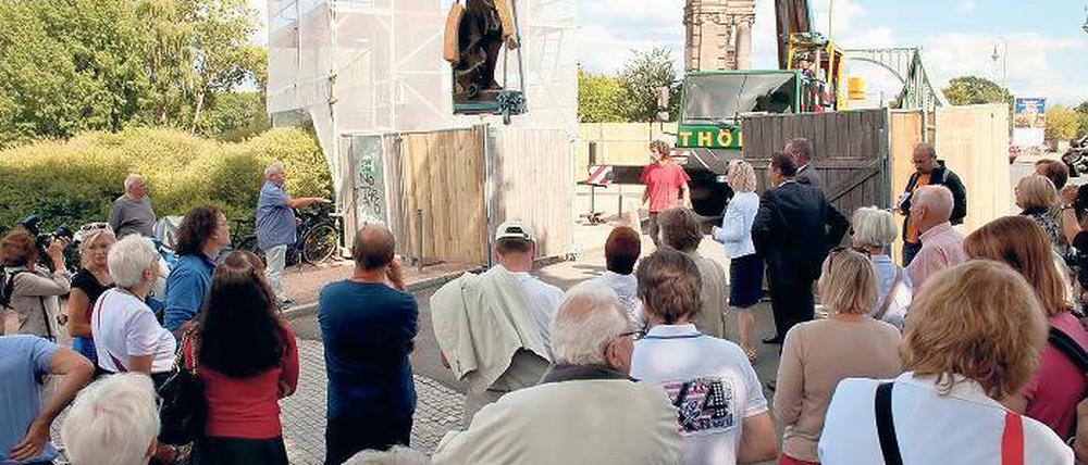 Eingehüllt. Als erstes soll der einzeln stehende Pylon (l.) der Kolonnaden der Glienicker Brücke restauriert werden. Dafür wurden am Montag im Beisein vieler Schaulustiger zunächst die beiden Sandsteinfiguren per Kran hinuntergehoben. Noch vor Winterbeginn sollen die 40 000 Euro teuren Arbeiten abgeschlossen sein.