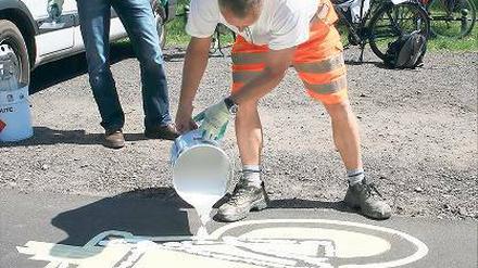 Aufbringen von „Zwei-Komponenten-Gießharz“. Radbeauftragter von Einem (li.) und Fachmann Brandt beim Anbringen eines Fahrradpiktogramms.