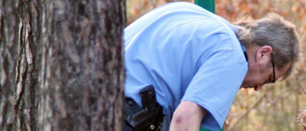 Ein Polizist sucht in Fichtenwalde in einem Mülleimer nach Beweismittel. Ein brutaler Überfall auf einen Zahnarzt in Fichtenwalde gibt der Polizei Rätsel auf.