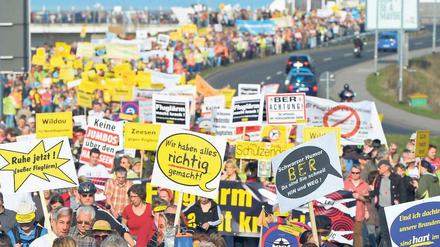 Krach gegen Krach. Mit Trillerpfeifen, Transparenten und Plakaten protestieren am Samstag laut Veranstalter etwa 10 000 Demonstranten nahe dem Flughafen Berlin-Brandenburg (BER) gegen den Fluglärm.