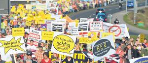 Krach gegen Krach. Mit Trillerpfeifen, Transparenten und Plakaten protestieren am Samstag laut Veranstalter etwa 10 000 Demonstranten nahe dem Flughafen Berlin-Brandenburg (BER) gegen den Fluglärm.